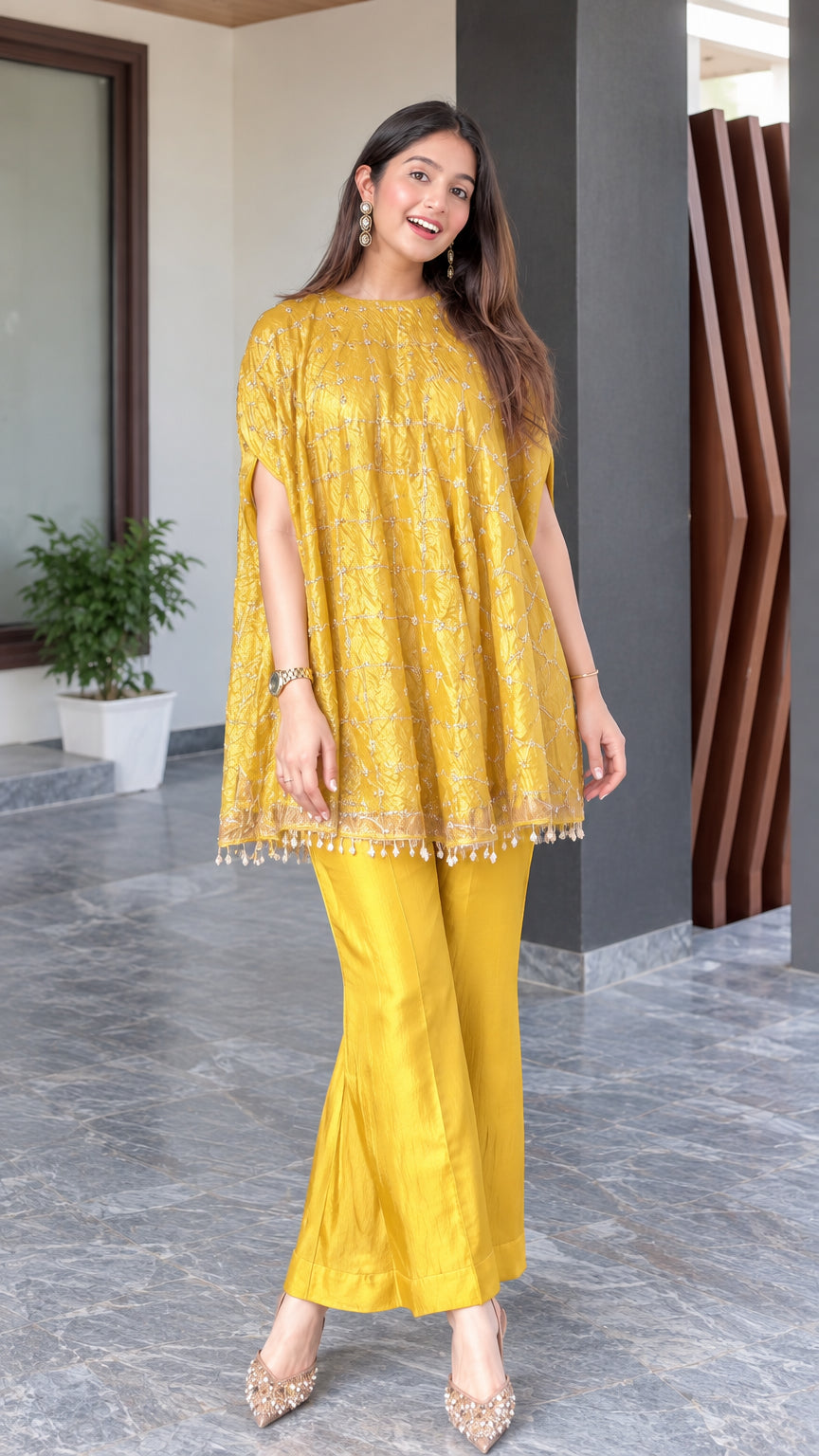 Full front view of model wearing mustard yellow embroidered cape top and flared pants set
