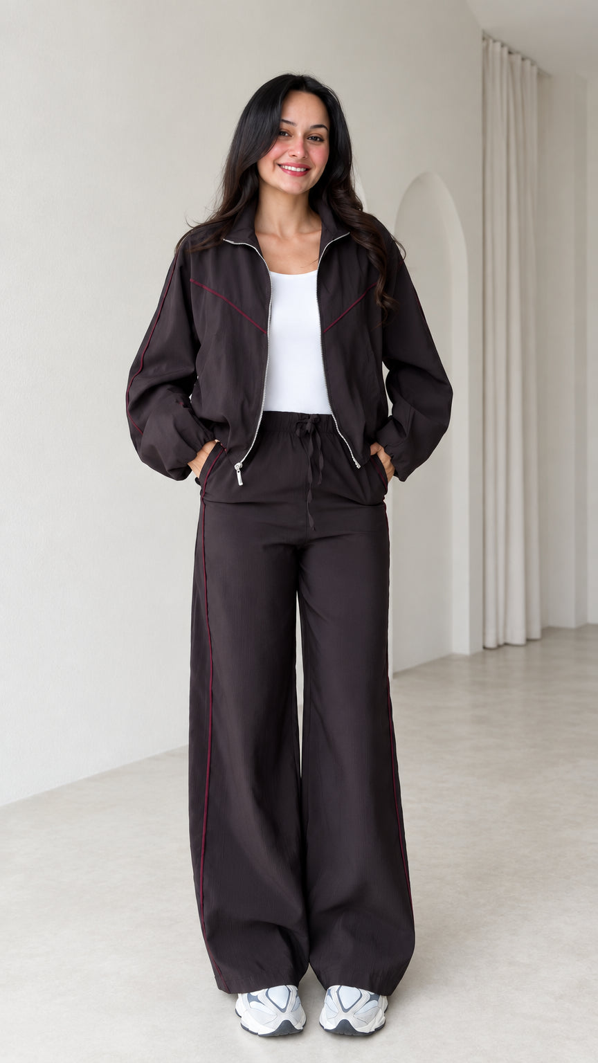 Front view of model wearing dark brown zip track jacket and matching wide leg pants set