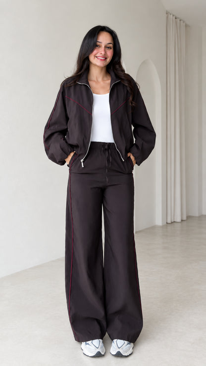 Front view of model wearing dark brown zip track jacket and matching wide leg pants set