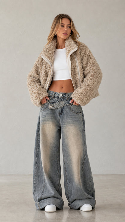 Front view of woman wearing beige cropped faux shearling teddy zip jacket with wide leg jeans