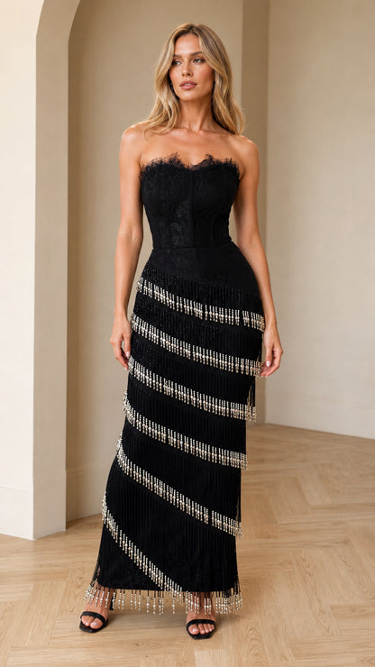 Front view of model wearing black strapless lace corset maxi dress with beaded fringe