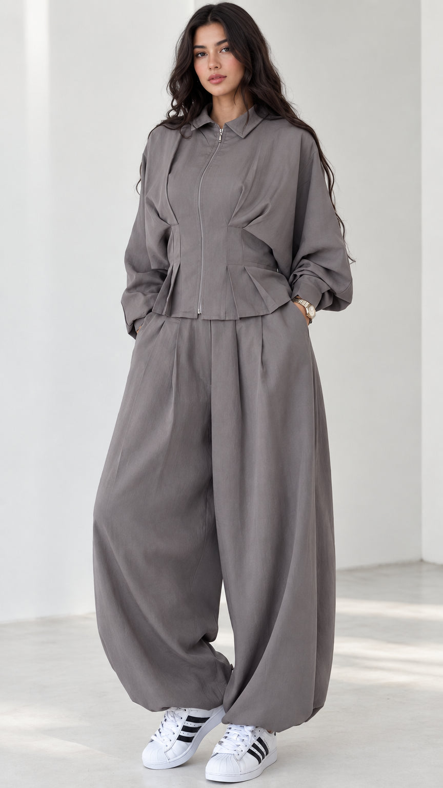 Model wearing grey zip-front top and balloon pants matching two-piece set front view