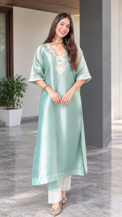 Front view of woman wearing sage green embroidered silk blend tunic kurta with white pants