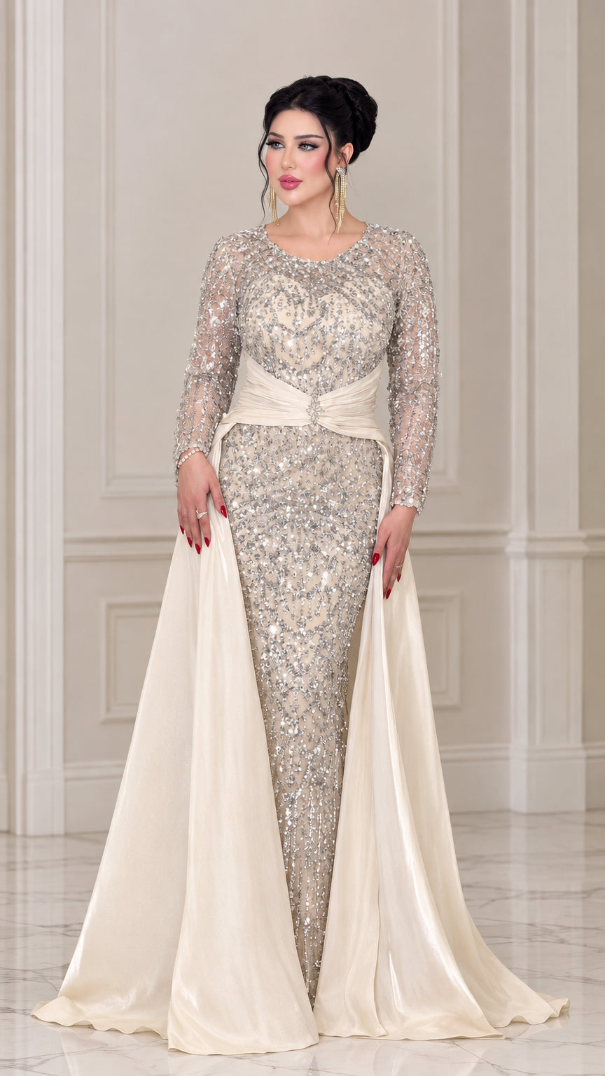 Front view of woman wearing a champagne sequin long sleeve evening gown with satin overskirt