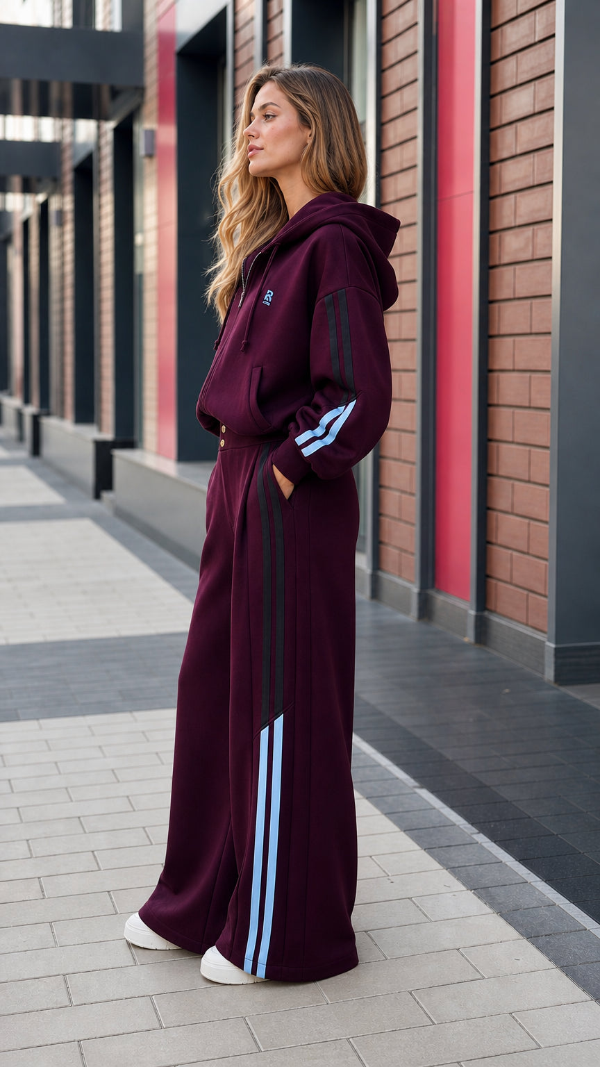 Side profile view of women's burgundy tracksuit with contrast light blue stripes