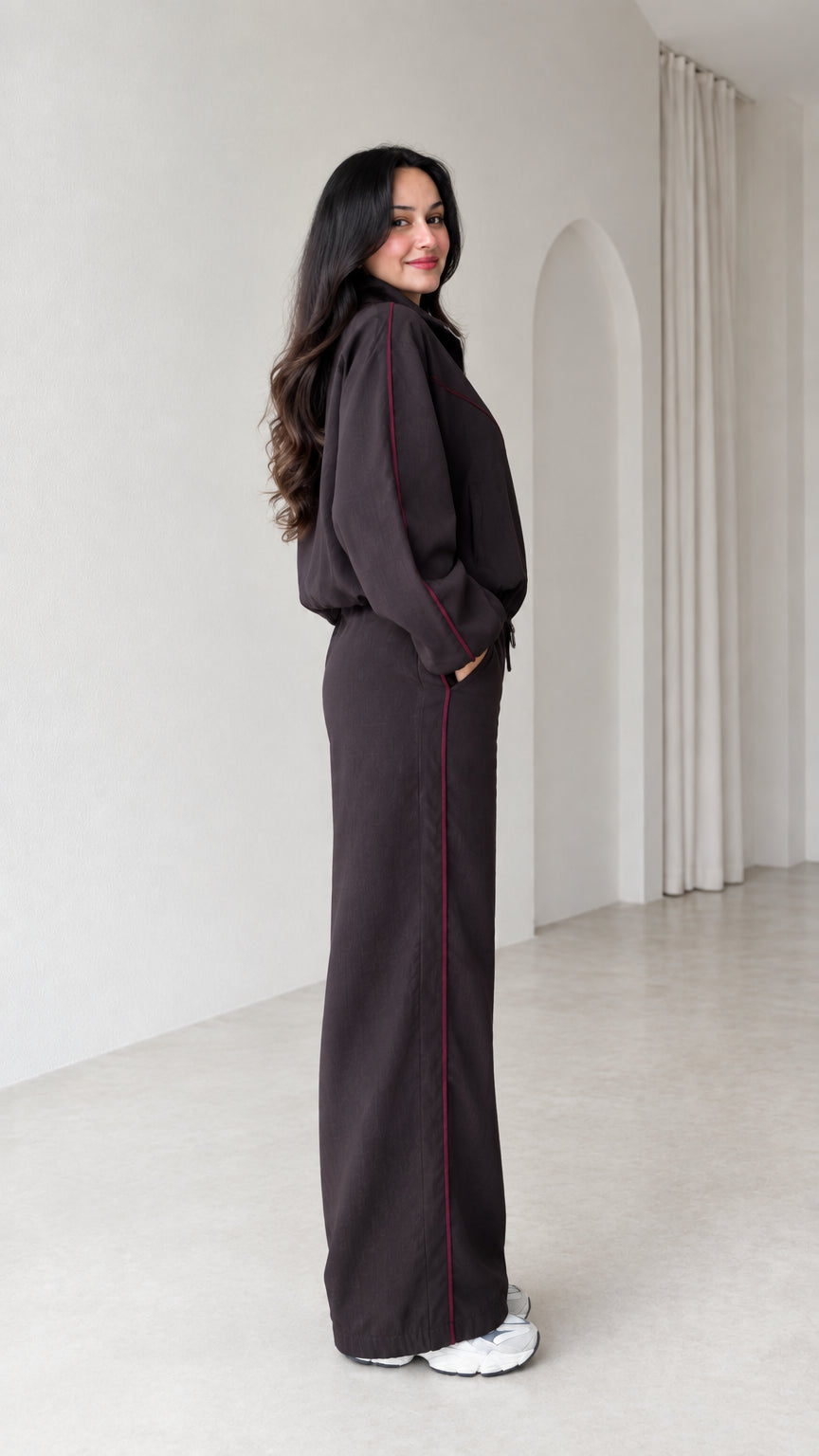 Side profile of model wearing dark brown two-piece tracksuit set with contrast piping