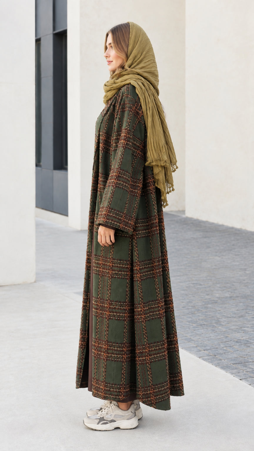 Side profile of woman wearing long olive green plaid cardigan coat
