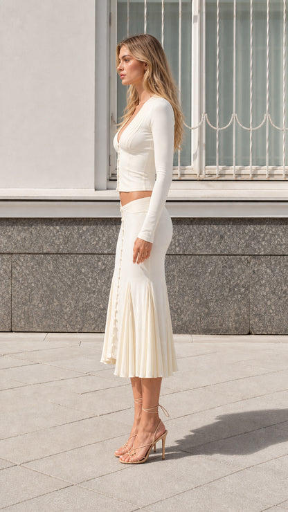 Side profile view of model wearing cream two-piece knit midi skirt set