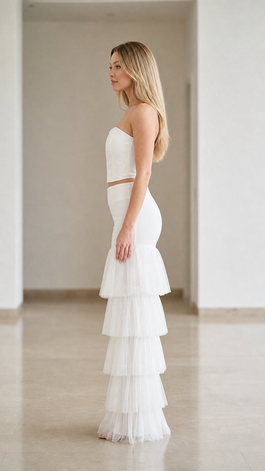 Side angle of white strapless corset top and tiered tulle ruffle trousers