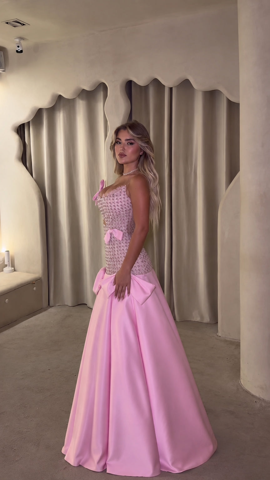 Side profile of pink crystal corset evening dress with flowing satin skirt
