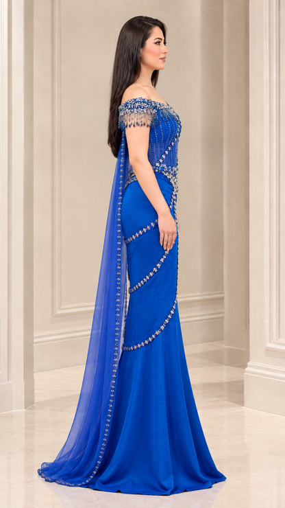 Side angle of model wearing Royal Blue embellished corset formal gown with flowing cape
