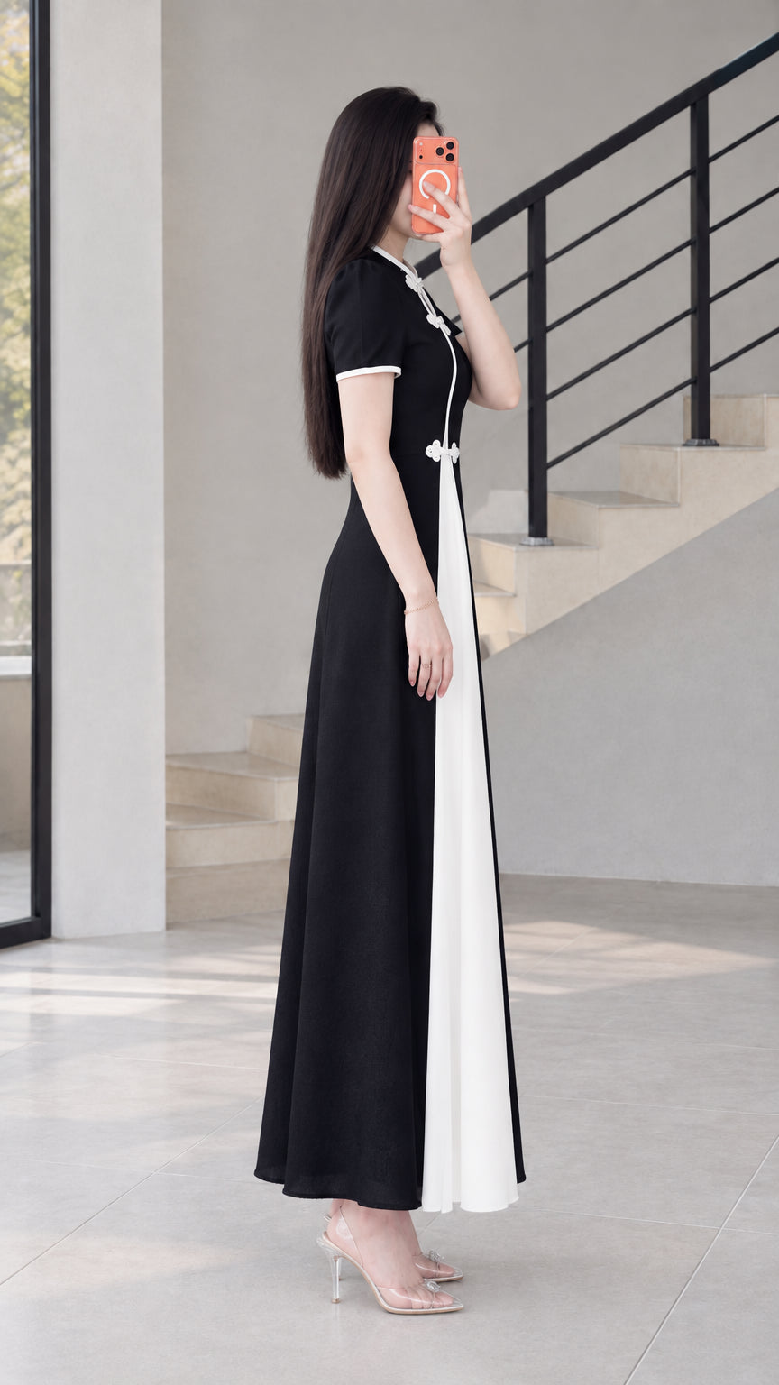 Side profile view of black contrast panel maxi dress with frog button accents