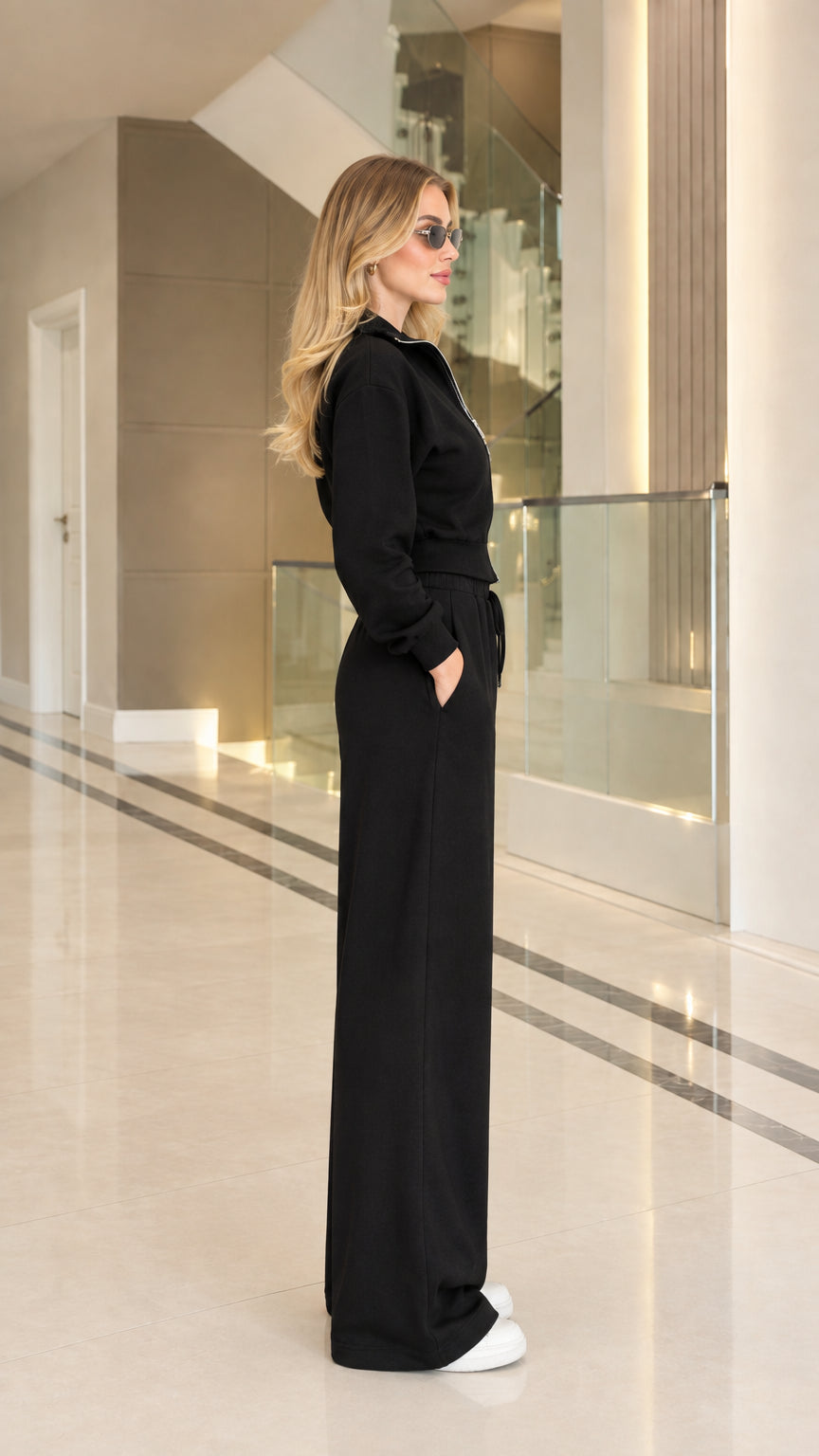 Side profile view of woman modeling black two-piece tracksuit outfit
