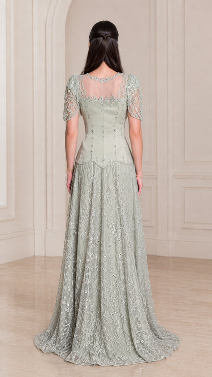 Back view of model wearing Sage Green beaded evening gown with illusion back