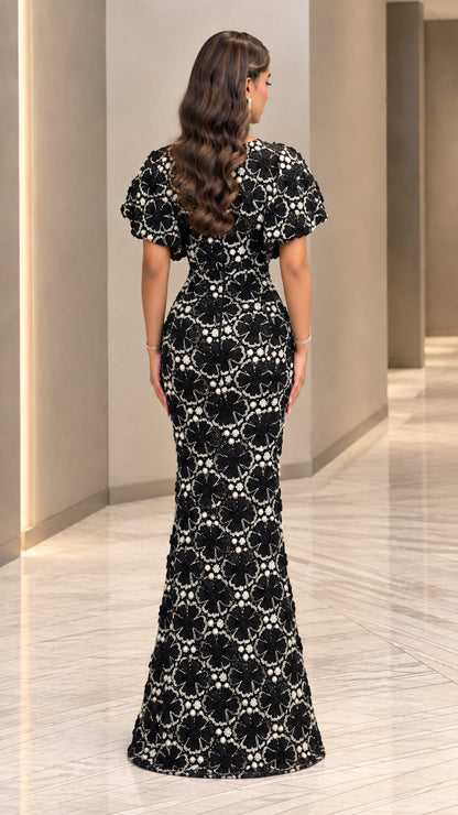 Back view of black 3D flower and pearl embroidered evening gown with capelet sleeves