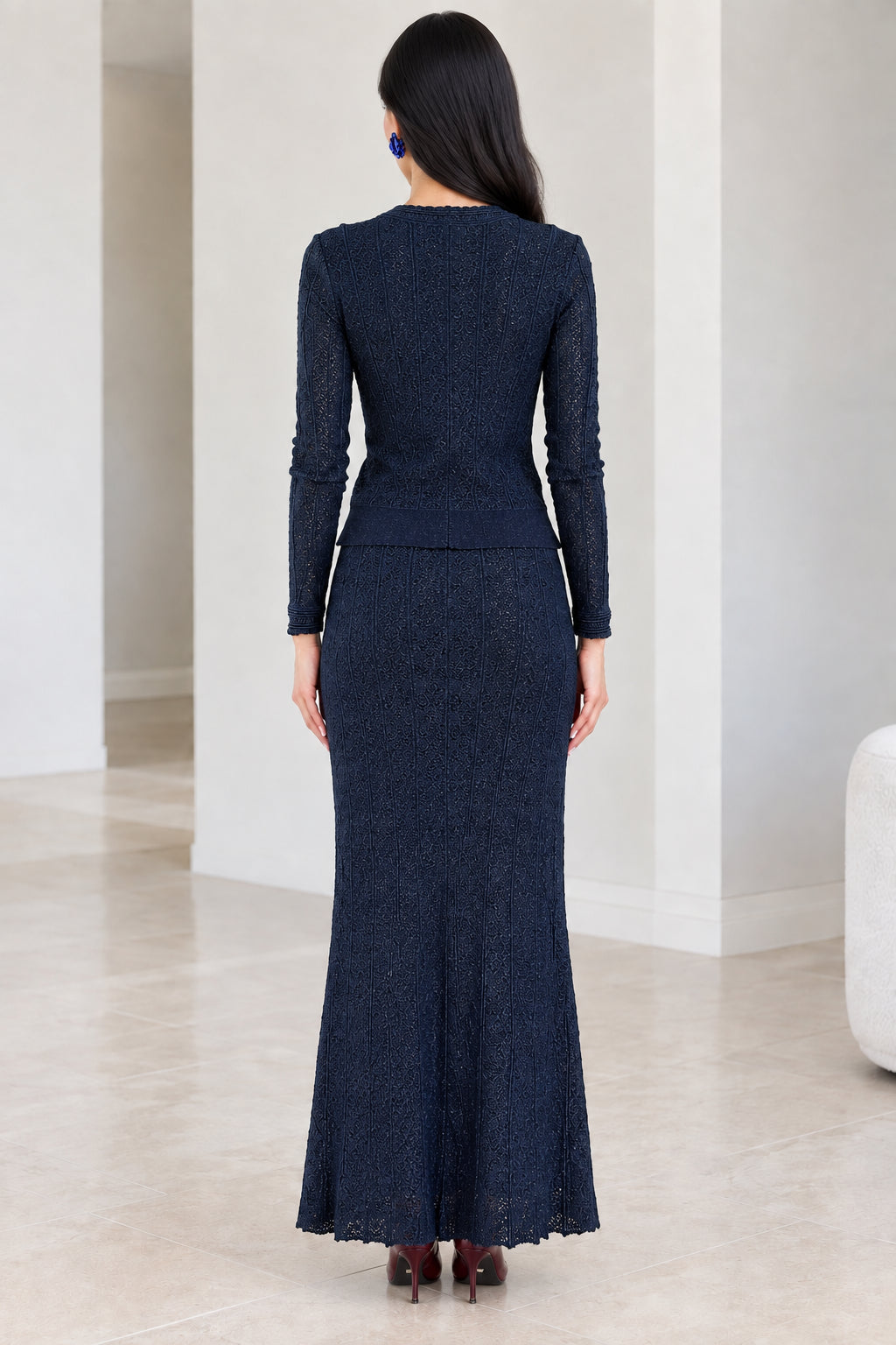 Back view of woman wearing navy blue textured long sleeve cardigan and skirt