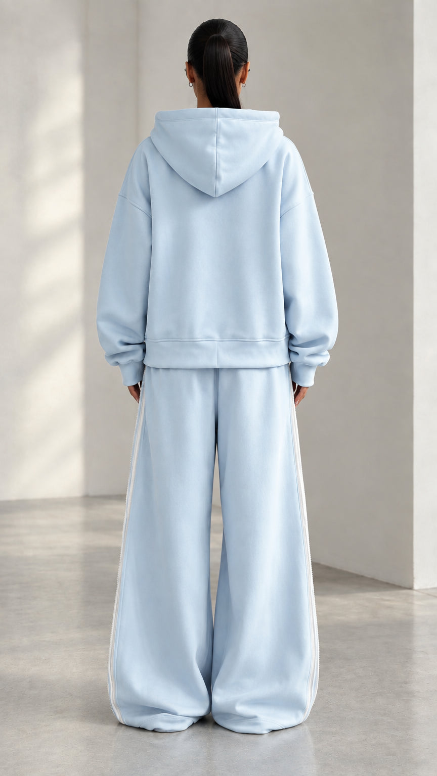 Back view of model wearing Light Blue hooded sweatshirt and matching wide-leg pants