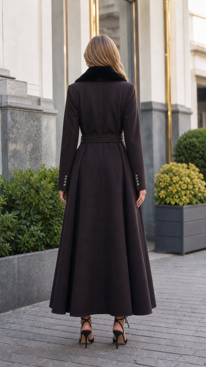 Back view of model in dark brown belted long coat showcasing pleated maxi hem