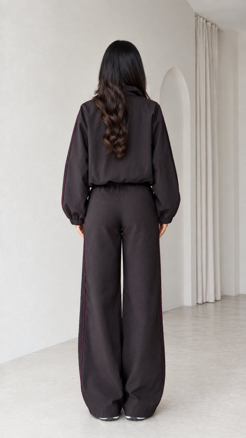 Back view of model in dark brown relaxed track jacket and wide leg pants