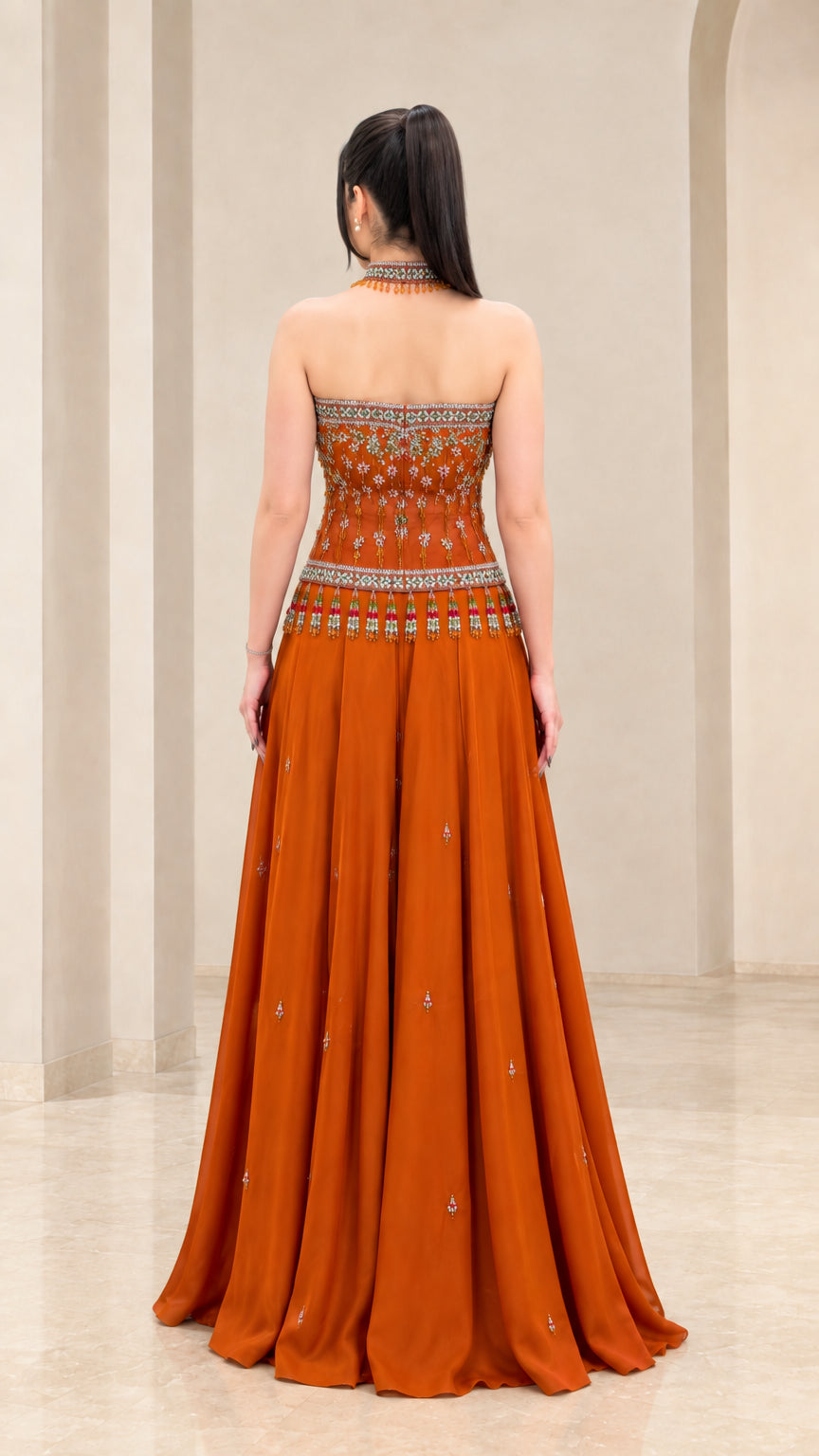 Back view of rust orange strapless formal gown showing floor-length pleated skirt