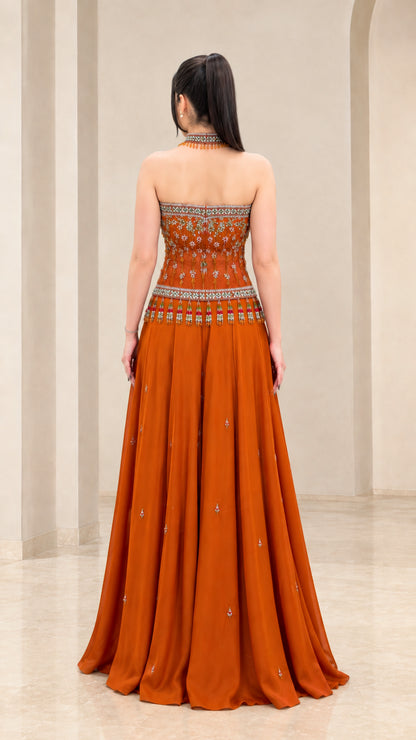 Back view of rust orange strapless formal gown showing floor-length pleated skirt