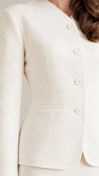 Close-up detail of ivory textured fabric, covered buttons, and jacket hemline