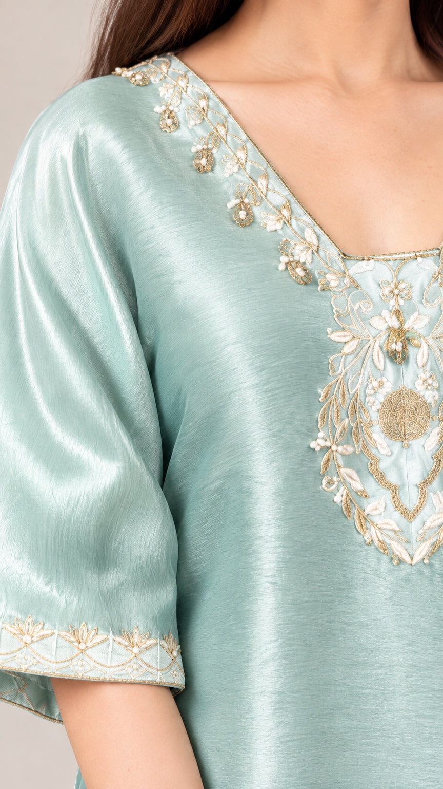 Close-up detail of metallic floral embroidery on V-neckline and sleeve cuff