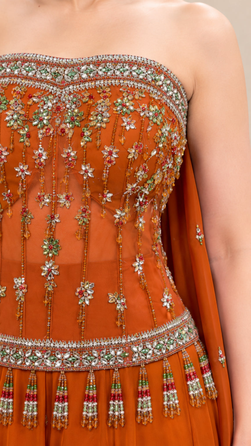 Close-up of rust orange embroidered bodice featuring crystal beadwork and fringe tassel trim