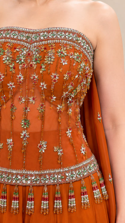 Close-up of rust orange embroidered bodice featuring crystal beadwork and fringe tassel trim