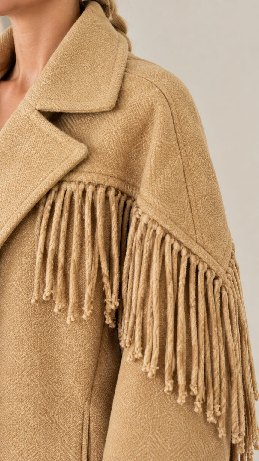Close-up detail of notched lapel collar, textured fabric, and tassel fringe