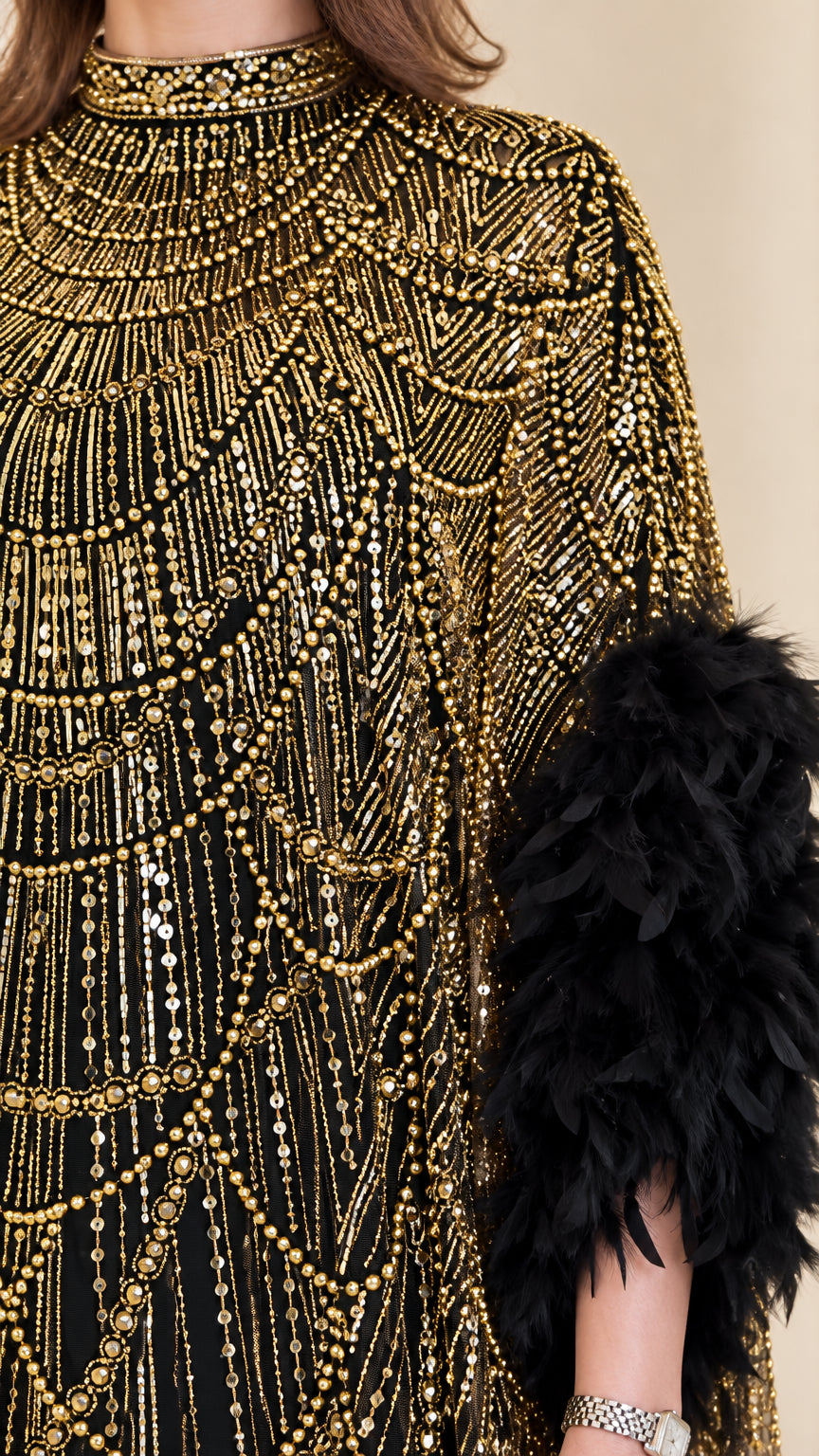 Close-up of intricate gold beading and black feather sleeve detail