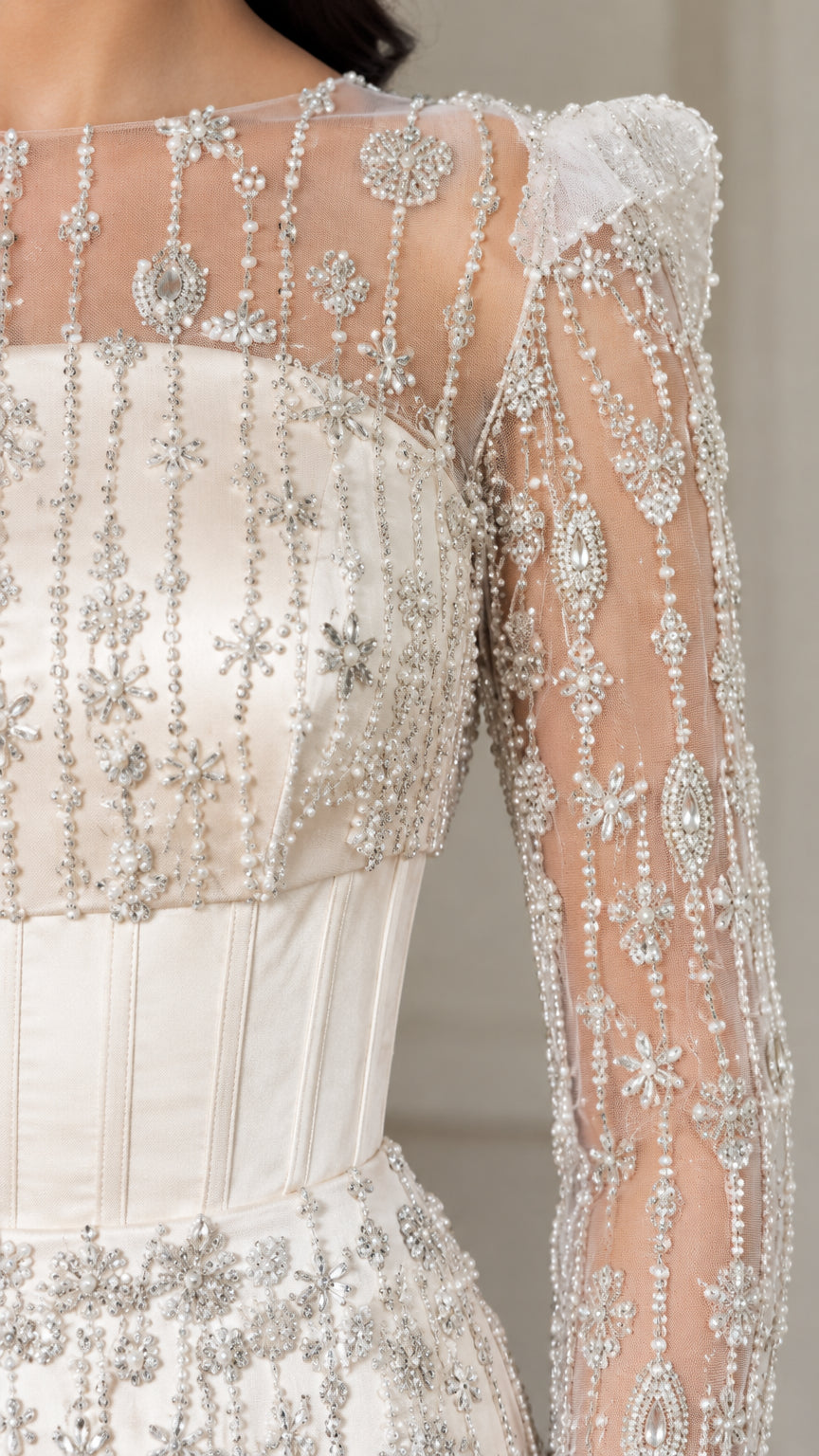 Close-up detail of silver beadwork and corset boning on ivory evening gown