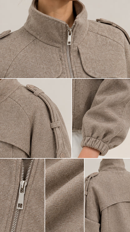 Close-up details of taupe utility jacket showing zip pull, shoulder straps, fabric texture, and elastic cuffs