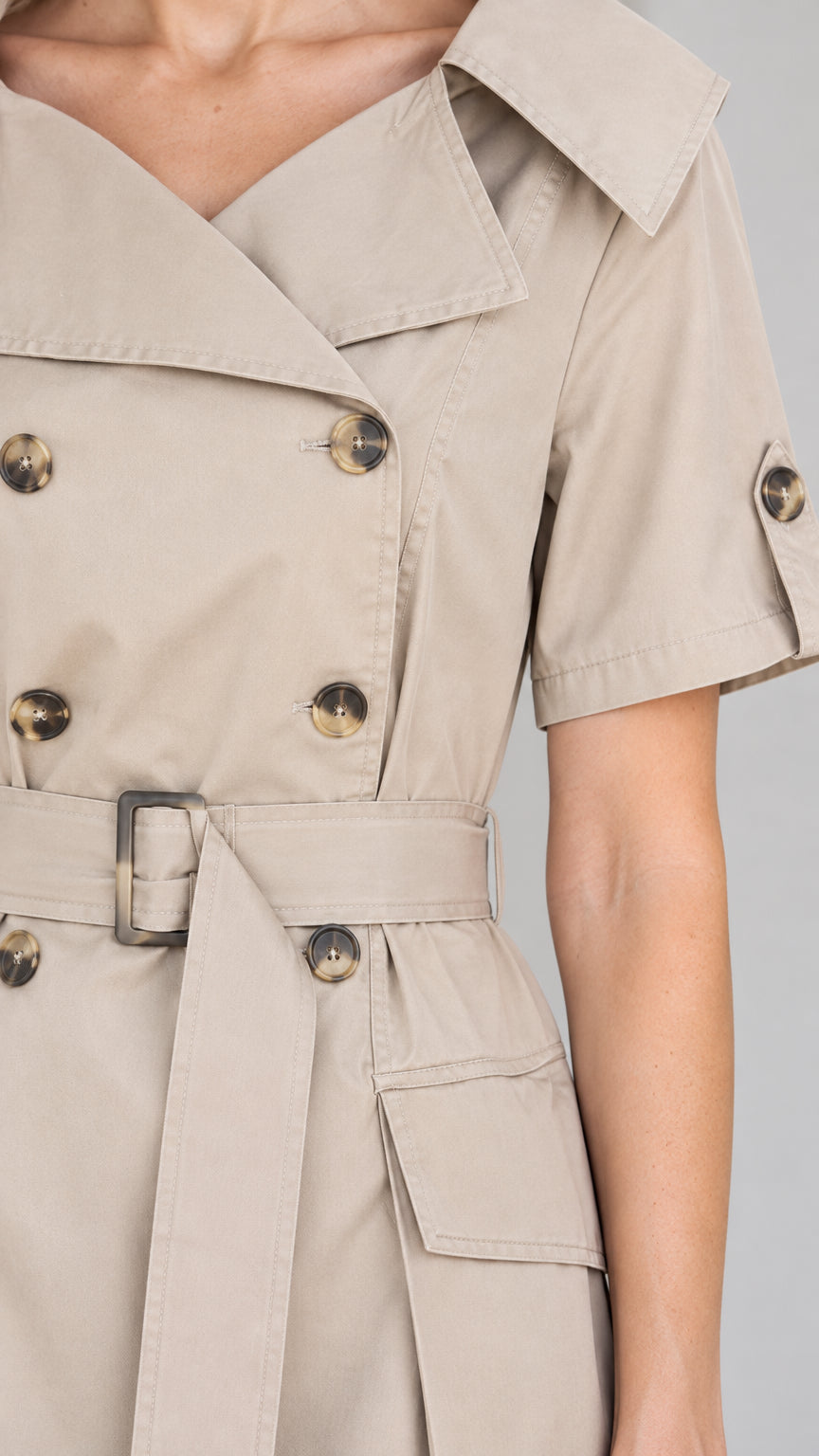 Close-up detail of beige trench dress lapel, buttons, cuff tab, and pocket flap