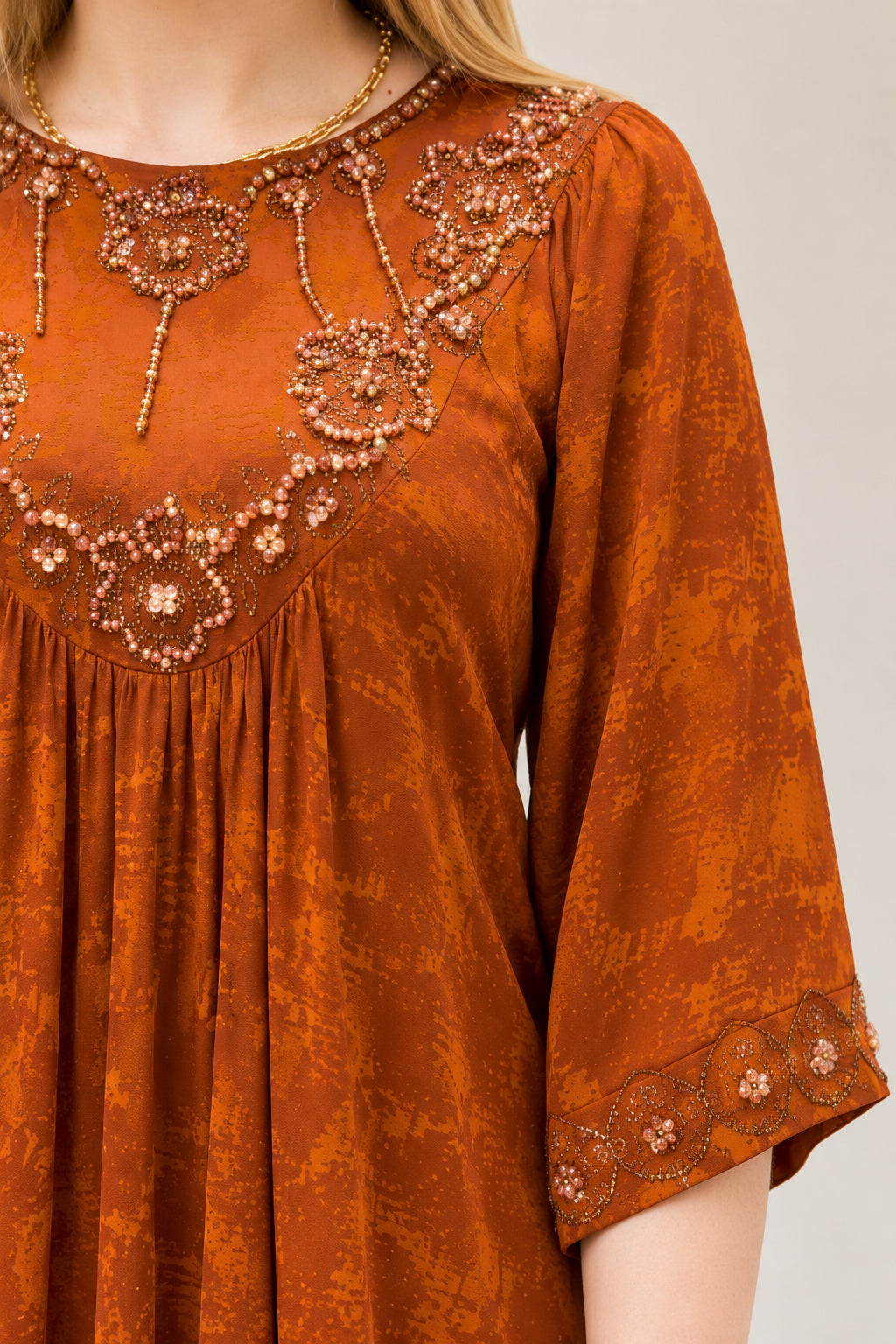 Close-up detail of embroidered beaded neckline and sleeve cuff on Rust Orange dress