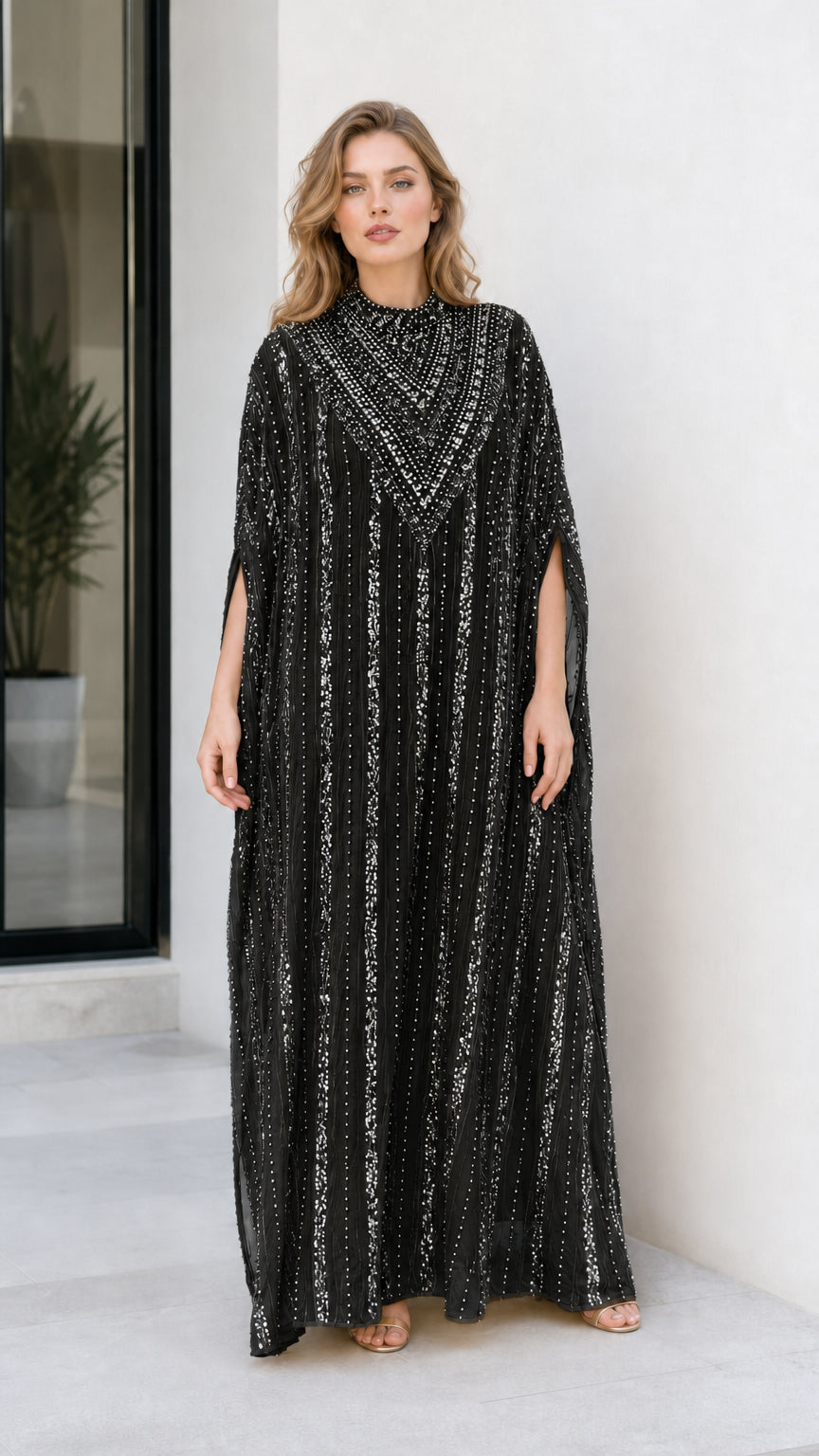 Model wearing black sequin embellished cape sleeve kaftan evening dress