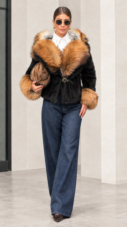 Woman wearing black plush short jacket with contrast camel faux fur trim and wide-leg denim