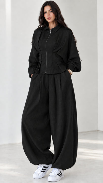 Model wearing black zip-front collared jacket and matching balloon pants set