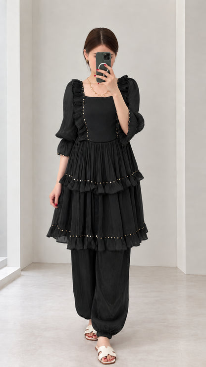 Front view of woman wearing Black tiered ruffle tunic and gathered-ankle pant set