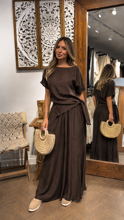 Woman wearing a chocolate brown draped waist maxi dress with a relaxed elegant fit