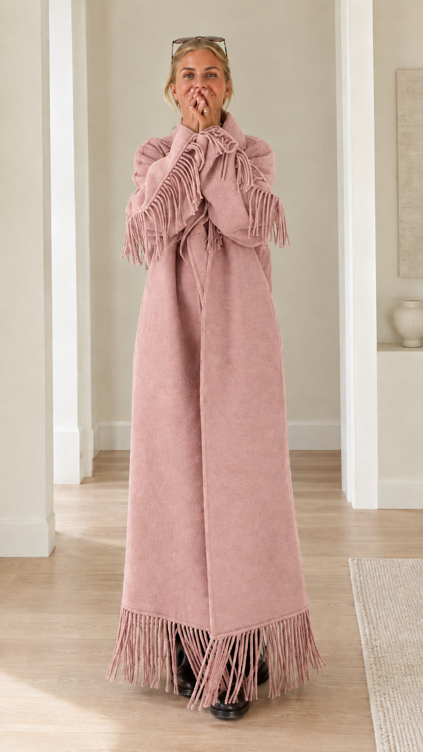 Full-length view of woman wearing blush pink fringe trimmed maxi overcoat