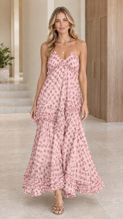 Model wearing a light pink polka dot tiered halter maxi dress