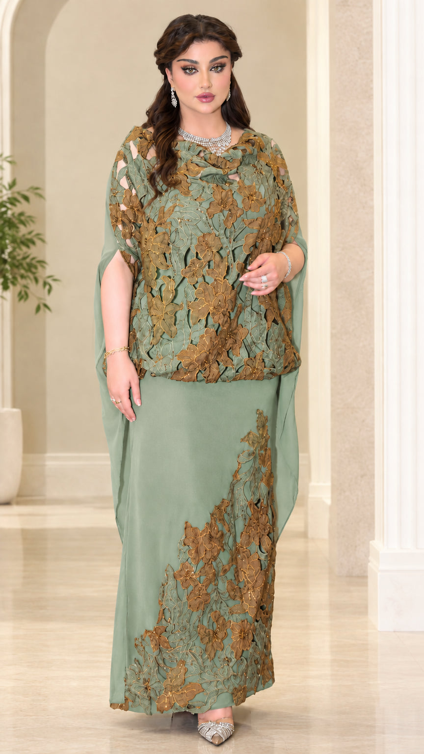 Model wearing sage green formal gown with gold lace cape overlay