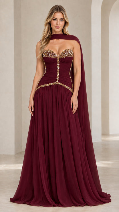 Model wearing burgundy red strapless embellished corset chiffon evening gown with matching neck scarf